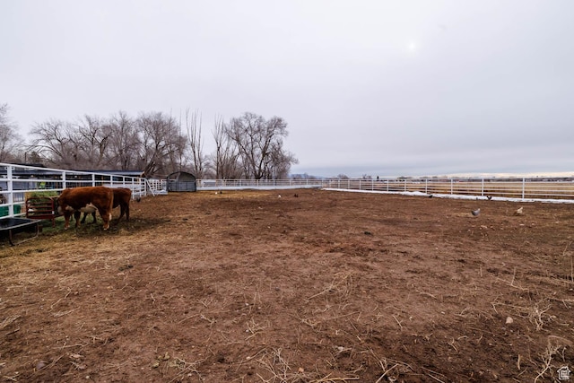 view of yard with an exterior structure, a rural view, an outdoor structure, and an enclosed area