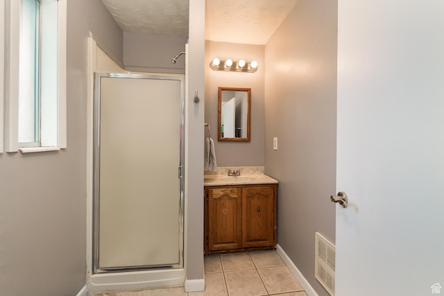 bathroom featuring tile patterned floors, baseboards, a shower stall, and visible vents
