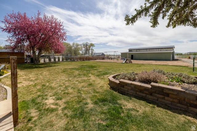 view of yard featuring fence, an outdoor structure, and a pole building