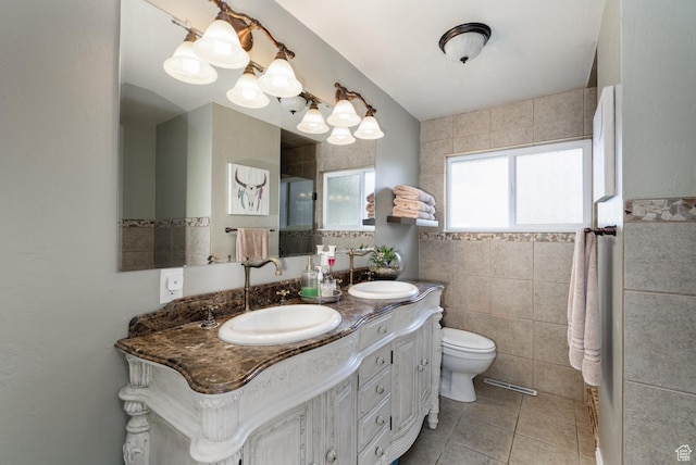 full bathroom featuring a sink, tile walls, toilet, and double vanity