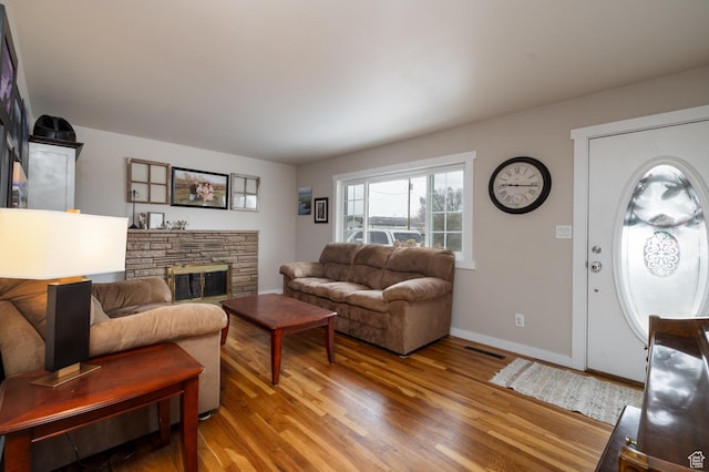 living room with light wood-style floors, baseboards, a fireplace, and visible vents