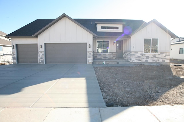 modern inspired farmhouse featuring stone siding, an attached garage, board and batten siding, driveway, and a porch