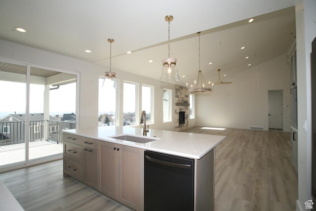 kitchen with open floor plan, light countertops, a sink, light wood finished floors, and dishwasher