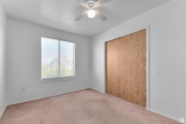 unfurnished bedroom with a closet, carpet floors, baseboards, visible vents, and ceiling fan