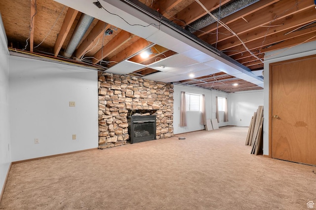 below grade area with a stone fireplace, baseboards, and carpet