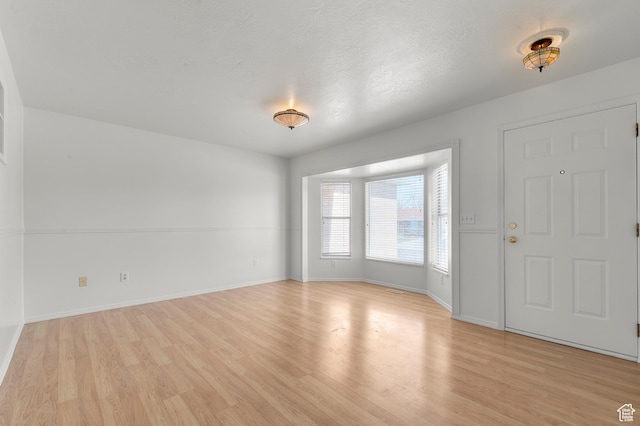 entryway with a textured ceiling, baseboards, and light wood-type flooring