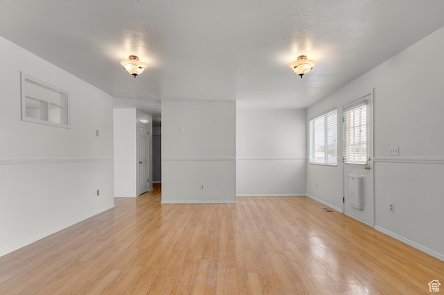spare room featuring baseboards and light wood-style floors