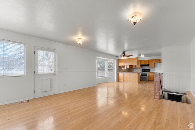 unfurnished living room with baseboards, visible vents, light wood-style flooring, and a ceiling fan