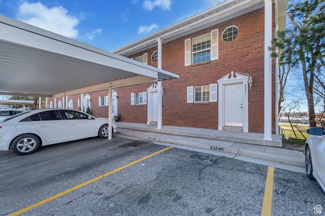exterior space with brick siding and covered and uncovered parking