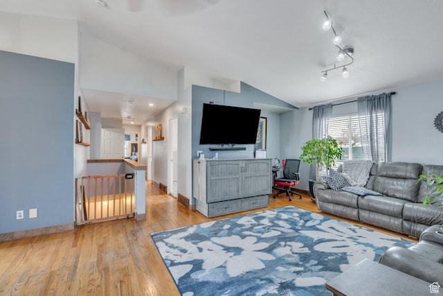 living area featuring baseboards, vaulted ceiling, and light wood-type flooring