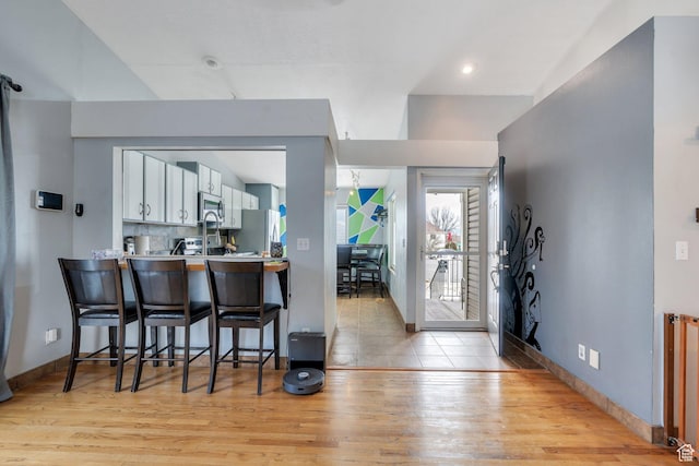 foyer entrance featuring baseboards, radiator, and light wood finished floors