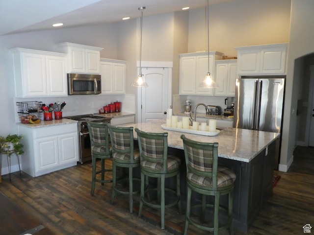 kitchen featuring dark wood-type flooring, white cabinets, a center island with sink, and appliances with stainless steel finishes
