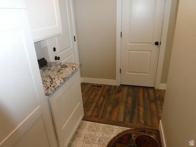 hall featuring baseboards and dark wood-style flooring