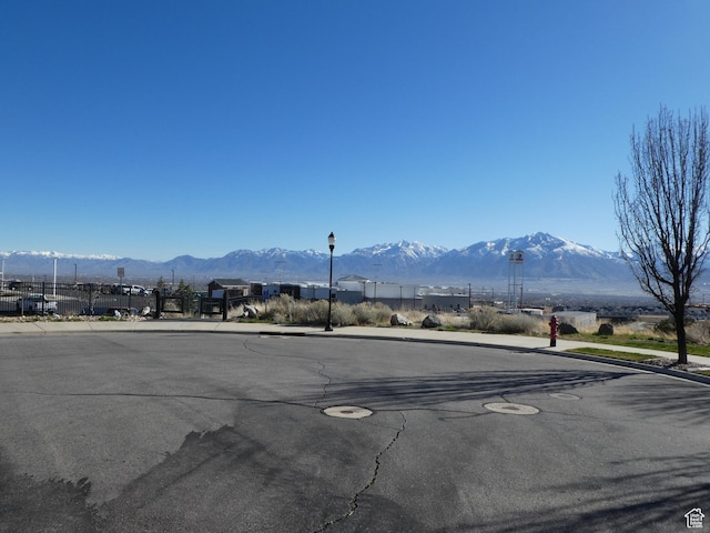 view of street with sidewalks, street lights, a mountain view, and curbs