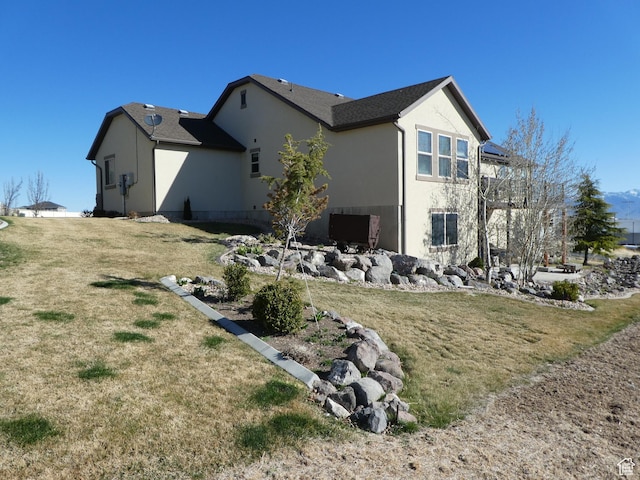 view of property exterior with stucco siding and a yard