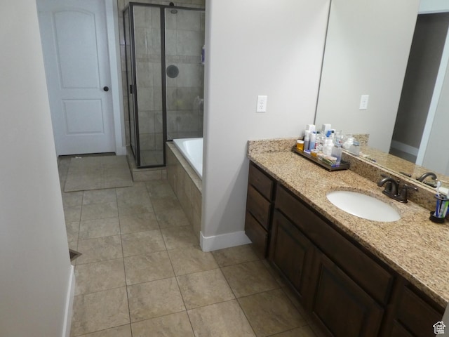 full bath featuring vanity, a shower stall, tile patterned flooring, baseboards, and tiled bath