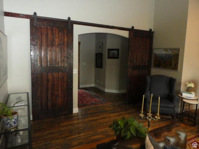 interior space with baseboards, wood finished floors, a barn door, and arched walkways