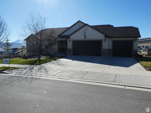 view of front of home featuring stone siding, driveway, a garage, and a mountain view