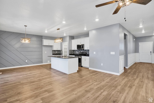 900 E Mecham Ave, Layton, UT 84040 - kitchen with light wood finished floors, stainless steel appliances, dark countertops, white cabinets, and ceiling fan