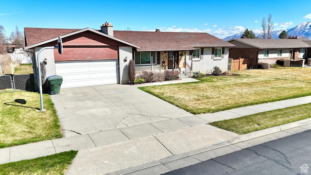 single story home featuring fence, an attached garage, driveway, a front yard, and brick siding