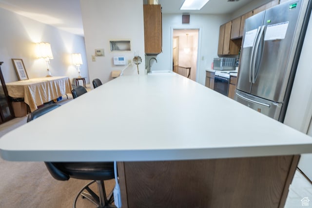 4971 S Beaver Brook Ln E Unit 40, Murray, UT 84117 - kitchen featuring light countertops, freestanding refrigerator, a kitchen breakfast bar, a peninsula, and range with electric stovetop