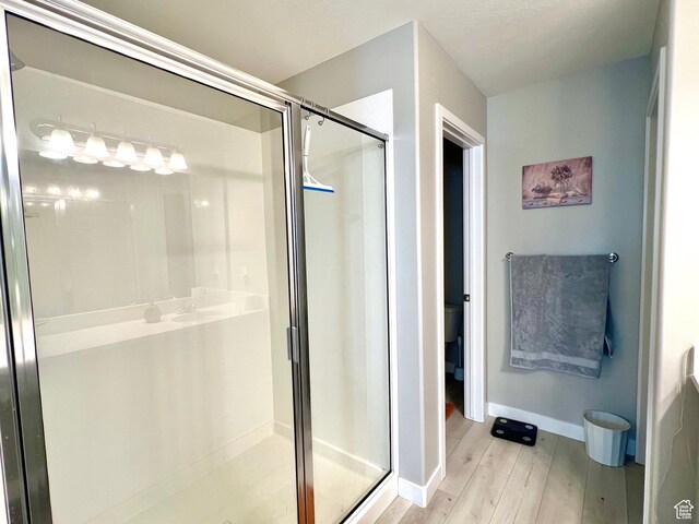 full bath with baseboards, wood finished floors, and a shower stall