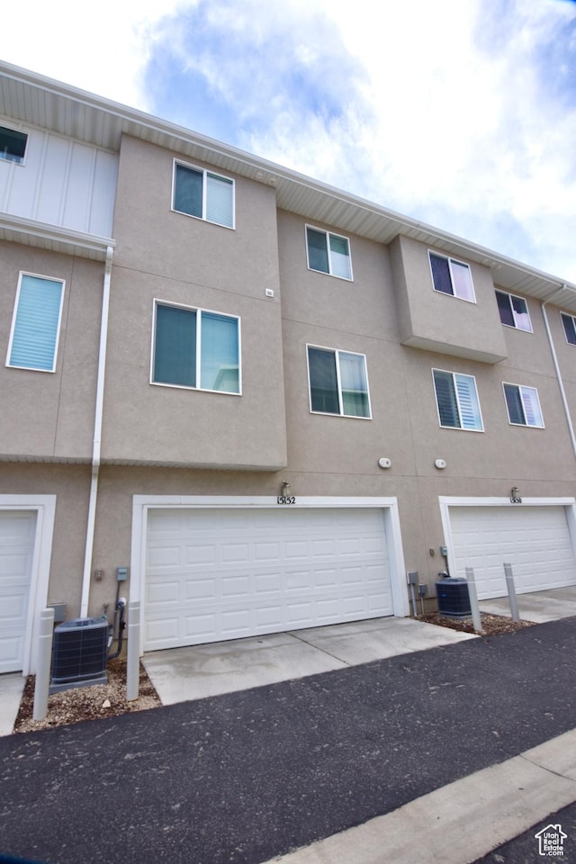 exterior space with stucco siding, an attached garage, and central AC