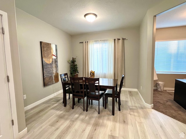 dining room with baseboards, light wood-style floors, and a textured ceiling
