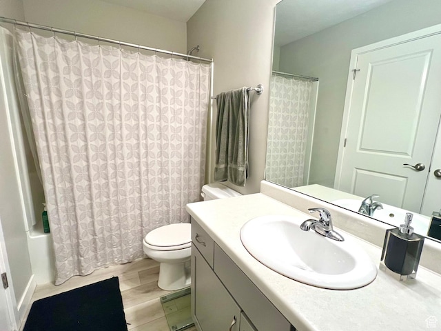 bathroom featuring toilet, wood finished floors, shower / tub combo with curtain, and vanity