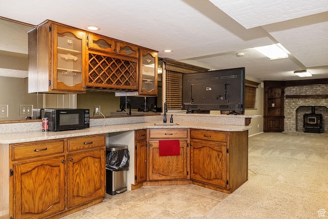 kitchen with black microwave, brown cabinets, a sink, and a peninsula