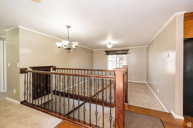 corridor featuring an upstairs landing, ornamental molding, baseboards, a chandelier, and wood finished floors