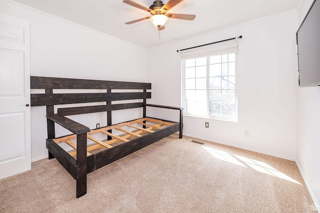carpeted bedroom featuring baseboards, visible vents, ornamental molding, and a ceiling fan