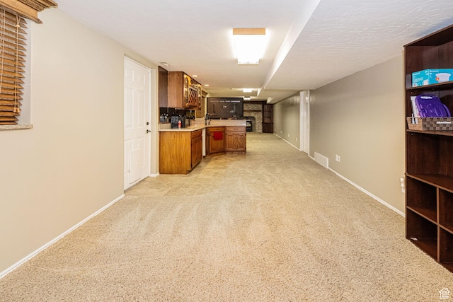 interior space featuring light countertops, a peninsula, baseboards, brown cabinetry, and light colored carpet