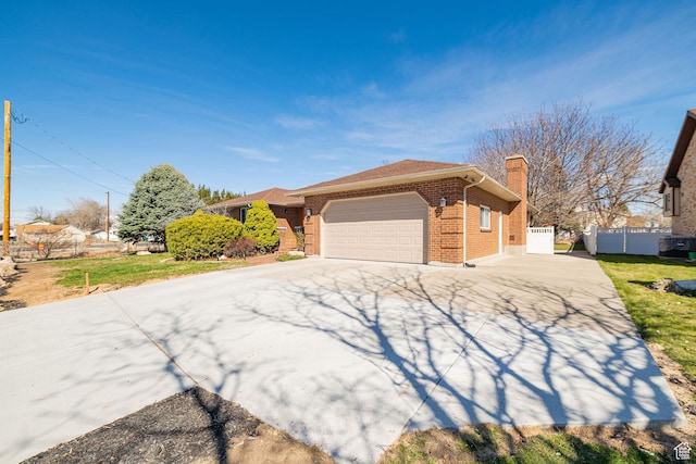 view of front of property with concrete driveway, fence, an attached garage, brick siding, and a chimney