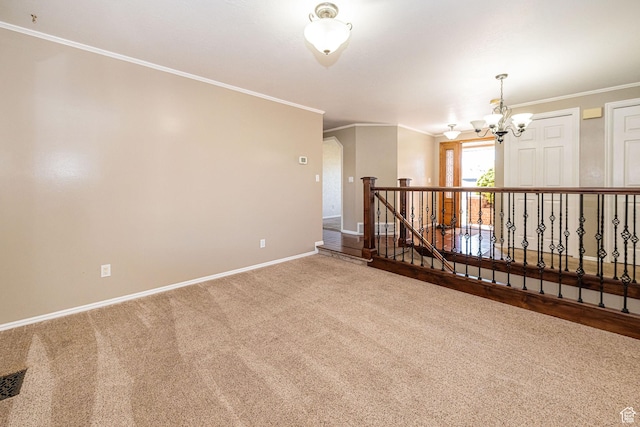 carpeted spare room with an inviting chandelier, crown molding, baseboards, and visible vents
