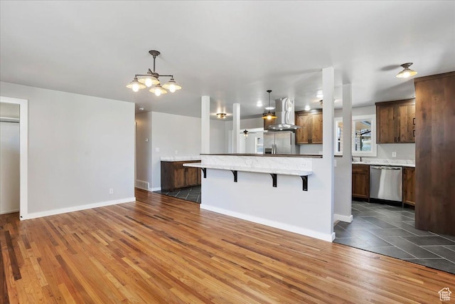 kitchen featuring a chandelier, a breakfast bar, wood finished floors, stainless steel appliances, and exhaust hood