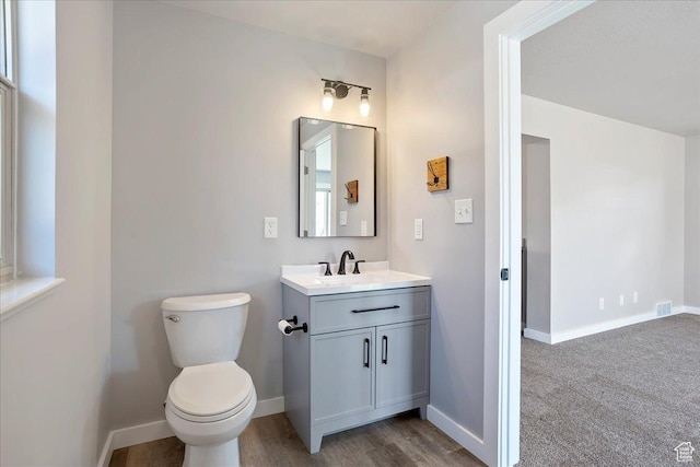 half bath featuring toilet, vanity, and baseboards