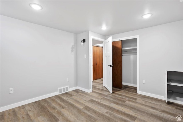 unfurnished bedroom featuring recessed lighting, baseboards, visible vents, a closet, and wood finished floors