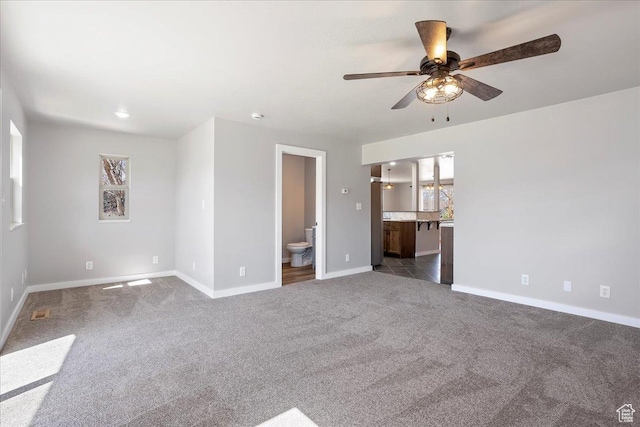 interior space with a ceiling fan, baseboards, dark carpet, and visible vents