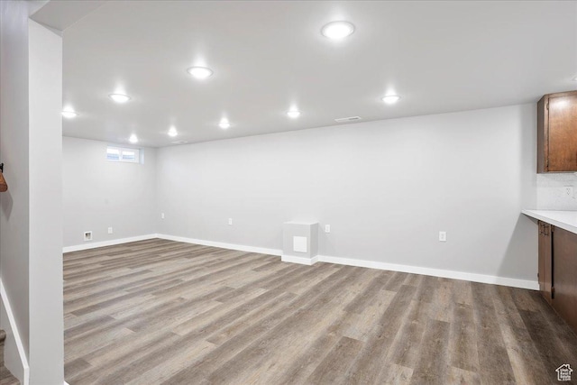 basement with baseboards, wood finished floors, and recessed lighting