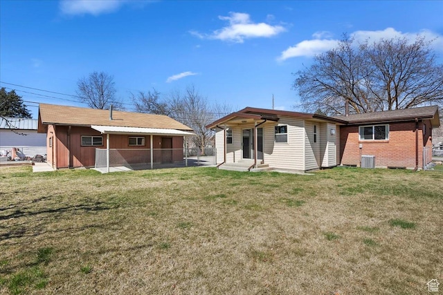 back of property with entry steps, central air condition unit, fence, and a yard