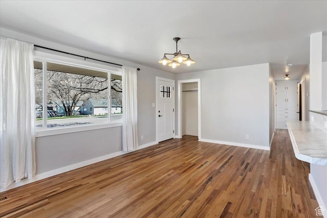 unfurnished dining area with baseboards, visible vents, wood finished floors, and an inviting chandelier