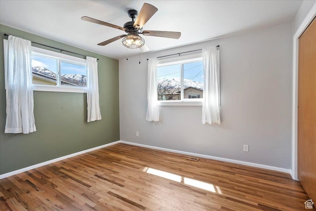 unfurnished room featuring baseboards, a wealth of natural light, visible vents, and wood finished floors