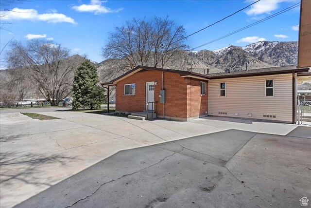 back of property featuring brick siding, fence, and a mountain view