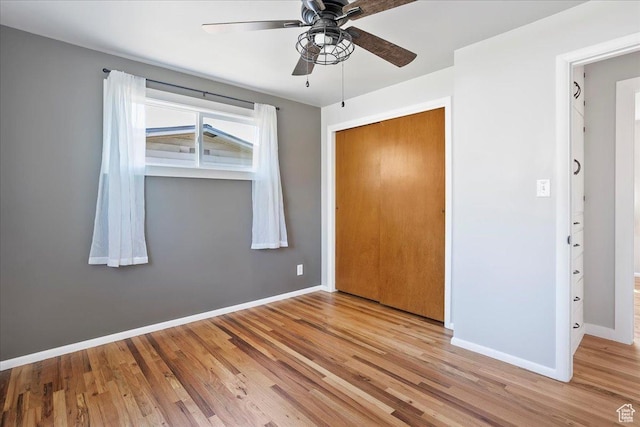 unfurnished bedroom featuring a closet, baseboards, ceiling fan, and wood finished floors