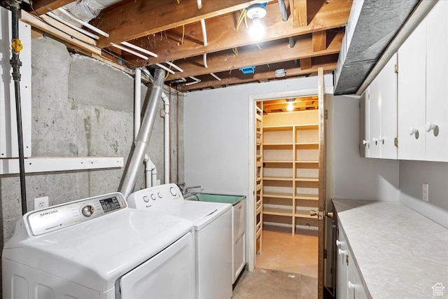 clothes washing area featuring cabinet space and washer and clothes dryer