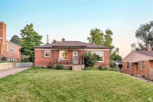 1311 E 29th St S, Ogden, UT 84403 - view of front of house with a front yard, covered porch, roof with shingles, central air condition unit, and brick siding