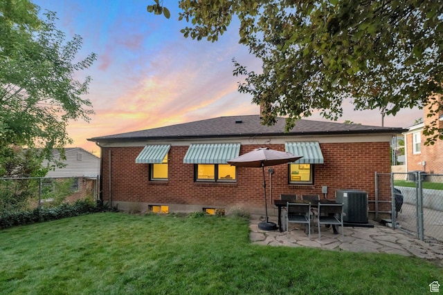 1311 E 29th St S, Ogden, UT 84403 - back of property at dusk featuring a gate, fence, brick siding, central AC, and a yard