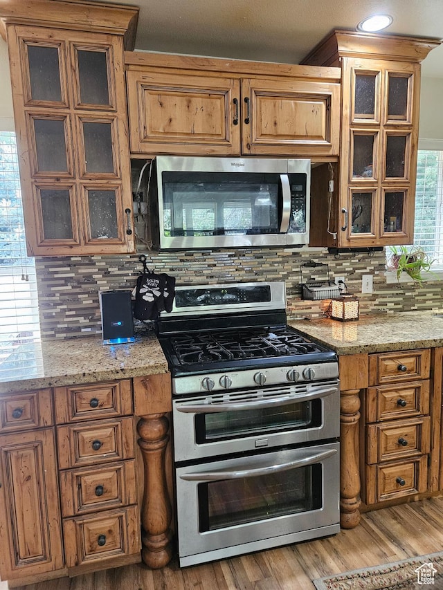 223 N 2520 W, Provo, UT 84601 - kitchen with light wood-style floors, brown cabinets, light stone countertops, decorative backsplash, and stainless steel appliances