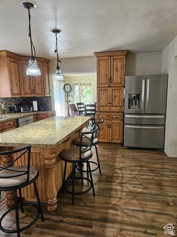 223 N 2520 W, Provo, UT 84601 - kitchen featuring appliances with stainless steel finishes, a breakfast bar, dark wood-style floors, brown cabinets, and light stone countertops